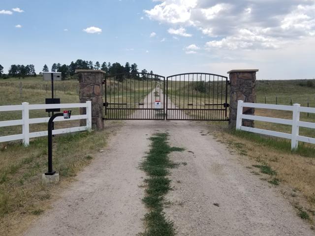 Arched gate with stone pillars and white rail fence
