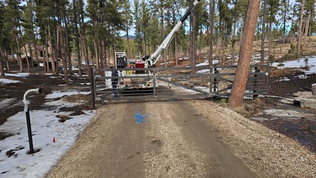 Crane installation of a custom gate in the pines