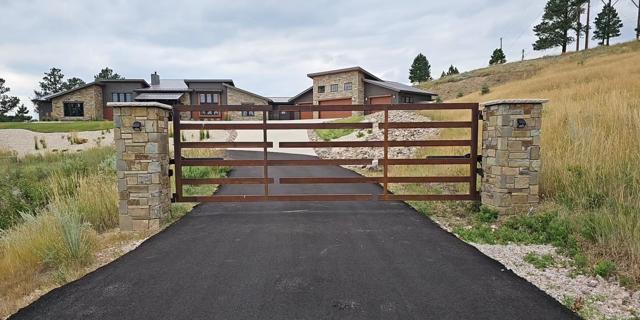 Modern corten steel gate with stone masonry pillars